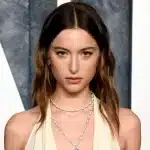 Eve Jobs wearing a white dress and layered necklaces at an event.