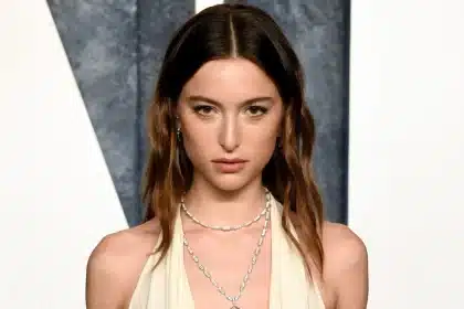 Eve Jobs wearing a white dress and layered necklaces at an event.
