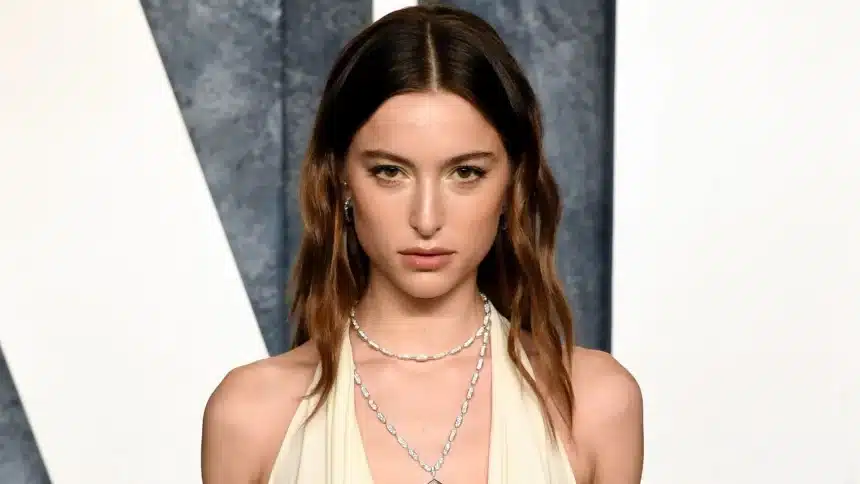 Eve Jobs wearing a white dress and layered necklaces at an event.