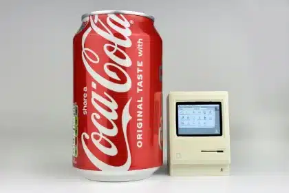A tiny Macintosh replica next to a Coca-Cola can for size comparison.