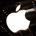 Large illuminated Apple logo on a glass building.