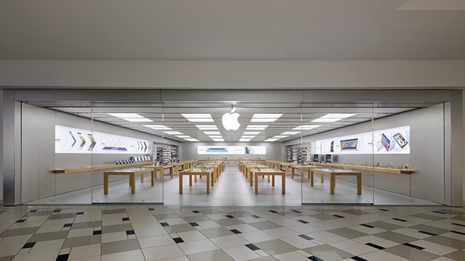 Empty Apple Store with wooden tables and glass entrance.