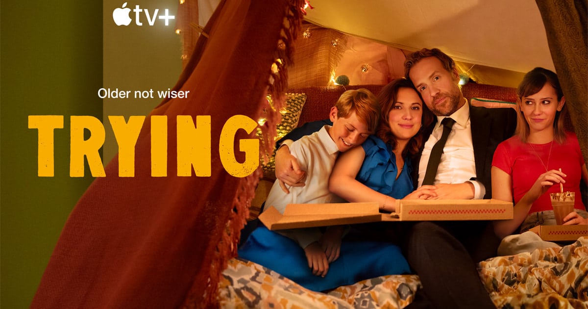 Cast of Apple TV+ series Trying sitting together with pizza in a cozy setting.