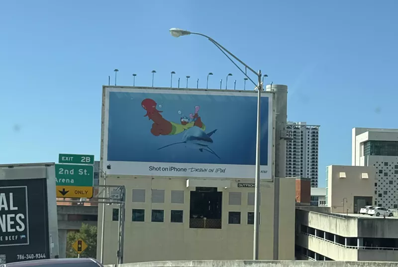 A billboard in Miami shows a cartoon of a person riding a shark with an octopus on their finger.