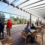 People sitting and walking on the Apple Park rooftop terrace with scenic views and wooden seating.