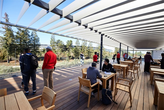 People sitting and walking on the Apple Park rooftop terrace with scenic views and wooden seating.