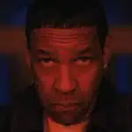 Denzel Washington stares intensely under red lighting.