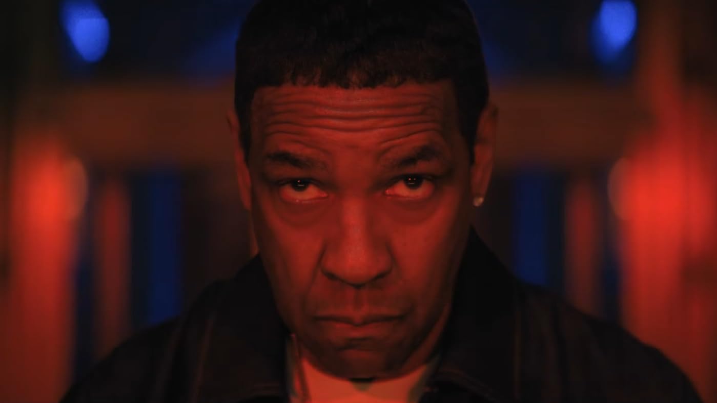 Denzel Washington stares intensely under red lighting.