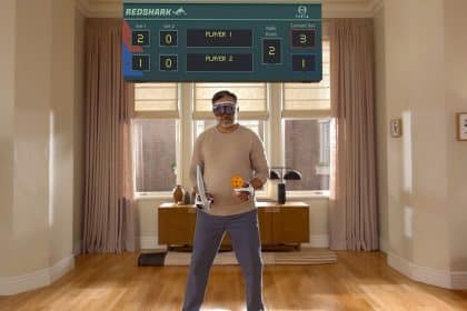 Man playing a virtual game using Apple Vision Pro headset and controllers.