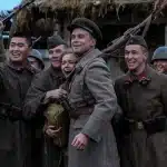 Group of soldiers in uniform smiling and posing together with rifles.