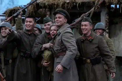 Group of soldiers in uniform smiling and posing together with rifles.