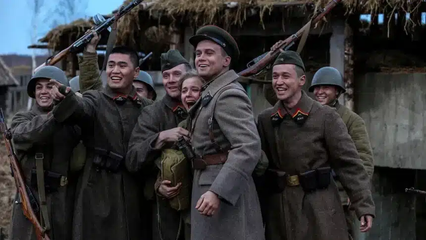 Group of soldiers in uniform smiling and posing together with rifles.