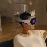 Person wearing Apple Vision Pro headset while sitting on a couch indoors.