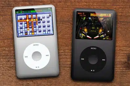 Two iPod Classics displaying clickwheel games on wooden surface.