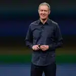 Apple executive standing on stage and smiling during a presentation.