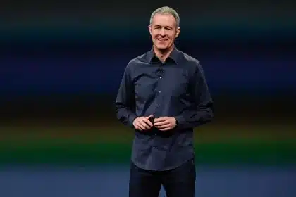 Apple executive standing on stage and smiling during a presentation.
