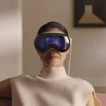 Person wearing an Apple Vision Pro headset while sitting indoors.