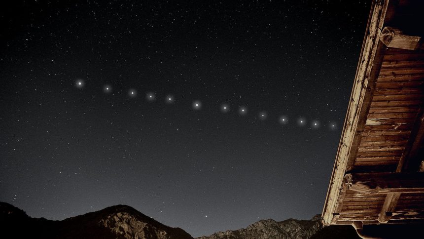 A line of bright Starlink satellites moving across a starry night sky above mountains and a wooden roof.