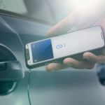 A person uses an iPhone to unlock a car with Apple Car Key technology.