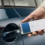 A person unlocking a car using an iPhone with Apple Car Key.