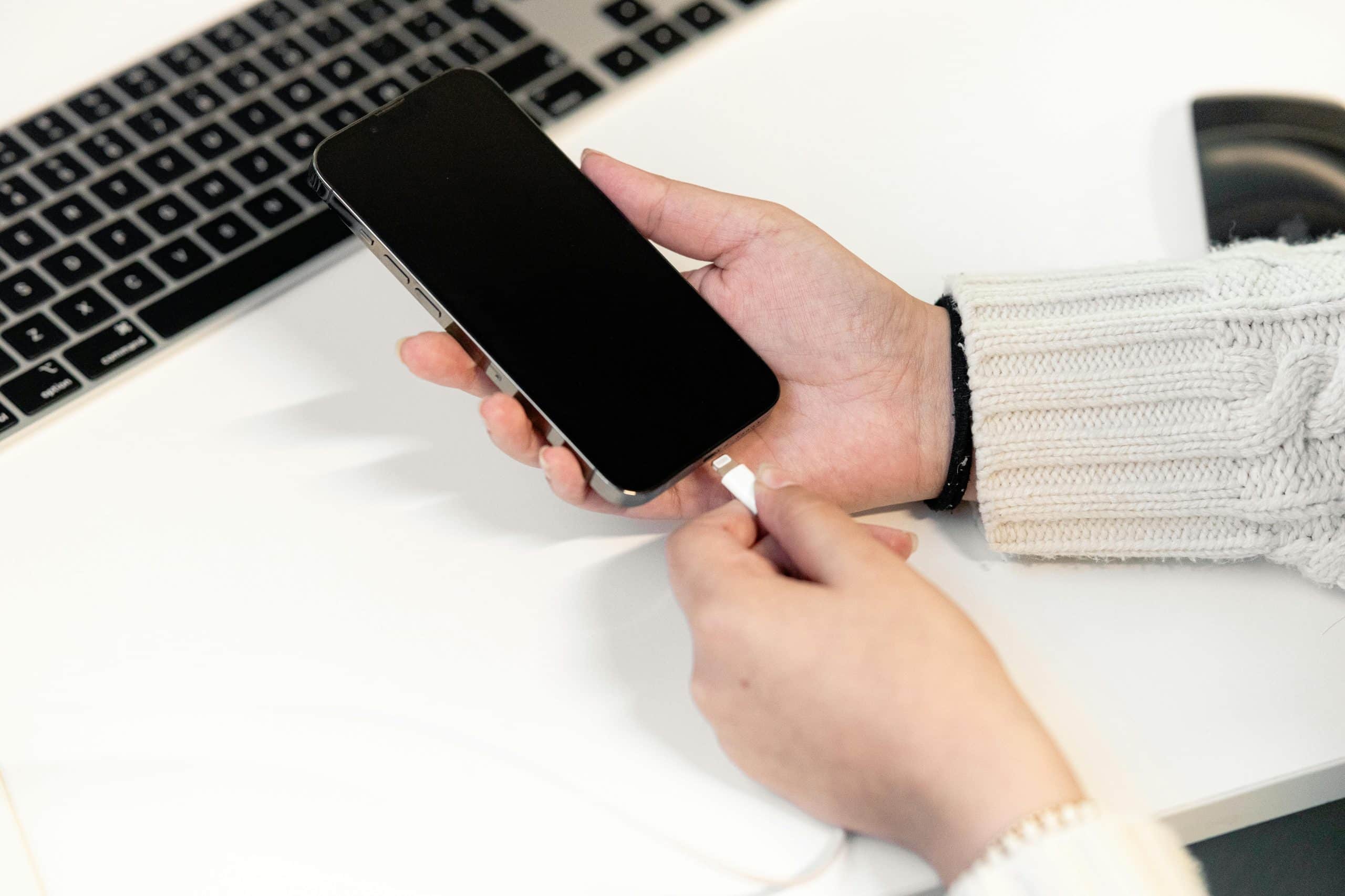 iPhone with low battery warning on nightstand, highlighting student concerns about overnight drain