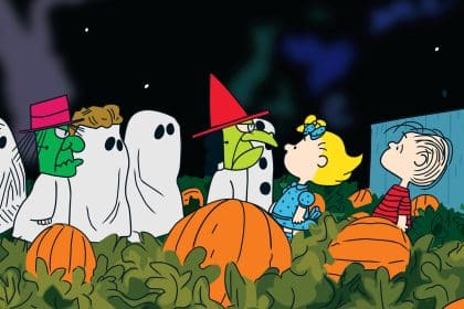 Peanuts characters in Halloween costumes standing in a pumpkin patch at night.