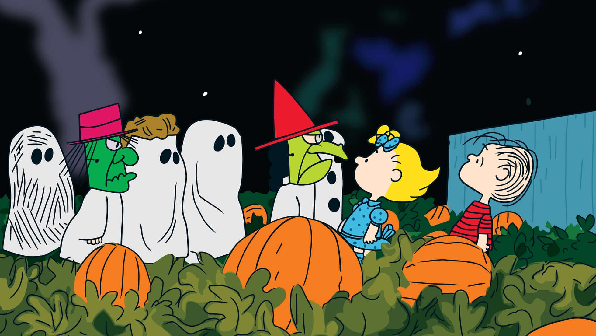 Peanuts characters in Halloween costumes standing in a pumpkin patch at night.