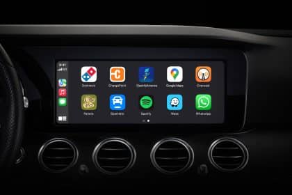 Car dashboard display showing Apple CarPlay apps on the screen.