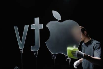 Person cleaning a large glass Apple TV logo under studio lighting.