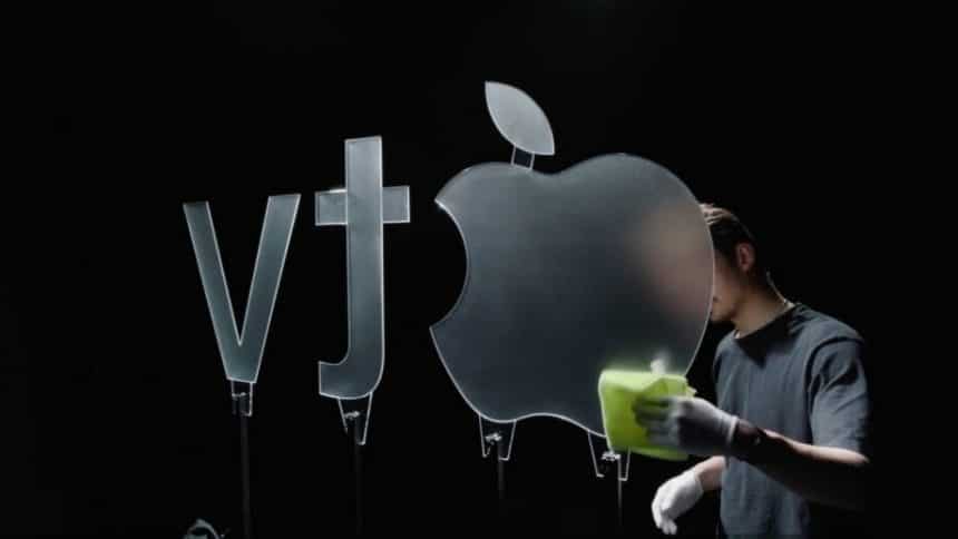 Person cleaning a large glass Apple TV logo under studio lighting.