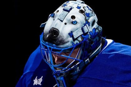 Hockey goalie wearing a blue jersey and a detailed wolf-themed goalie mask.