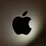 Close-up of the black Apple logo on a metallic surface.