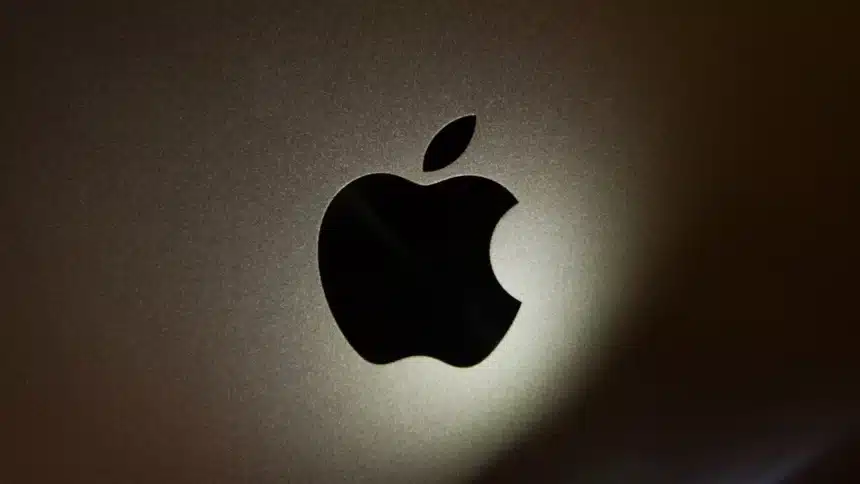 Close-up of the black Apple logo on a metallic surface.