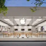 Apple Store exterior with glass front and logo illuminated at dusk.
