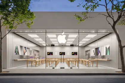 Apple Store exterior with glass front and logo illuminated at dusk.