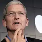 A man speaking on stage with an Apple logo in the background.