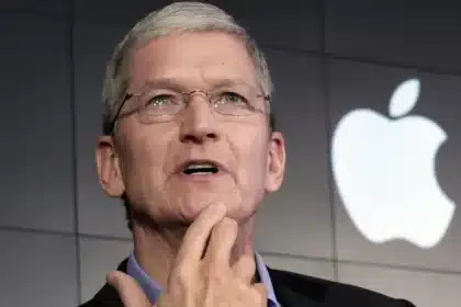 A man speaking on stage with an Apple logo in the background.