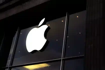 Apple logo glowing on a store window at night.