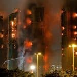 High-rise buildings engulfed in flames and thick smoke during a large nighttime fire.