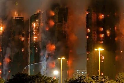 High-rise buildings engulfed in flames and thick smoke during a large nighttime fire.