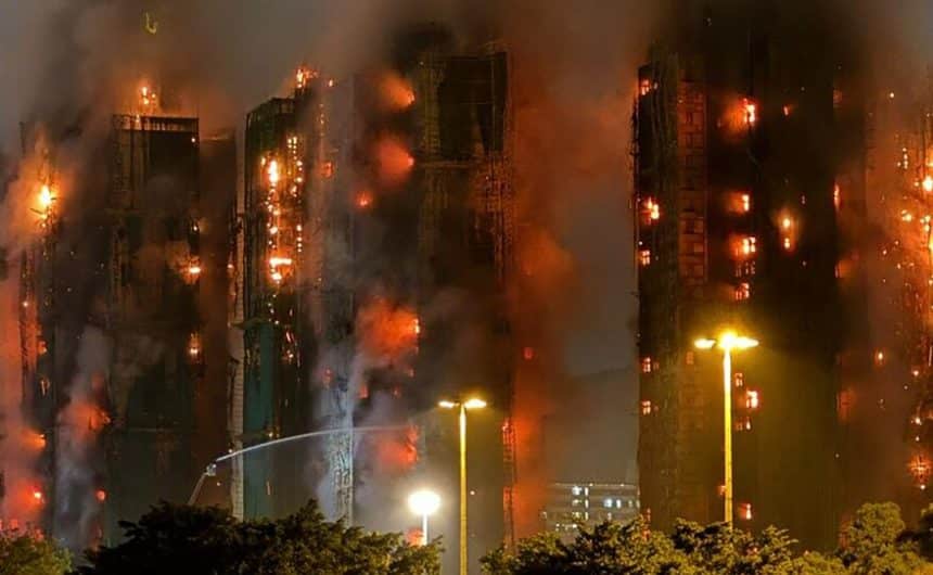 High-rise buildings engulfed in flames and thick smoke during a large nighttime fire.