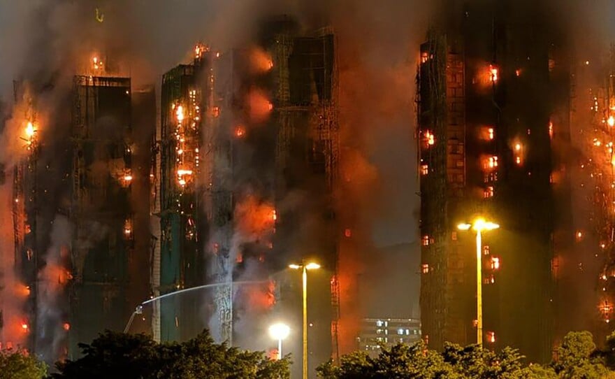 High-rise buildings engulfed in flames and thick smoke during a large nighttime fire.