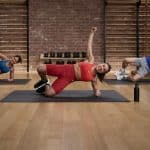 Apple Fitness+ trainers lead a group workout in a studio.