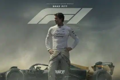 Brad Pitt standing beside a Formula 1 race car under a cloudy sky.