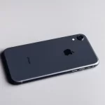 Black iPhone lying face down on a light surface.