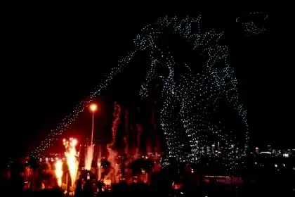 Night drone show creating a giant monster outline above the city skyline.