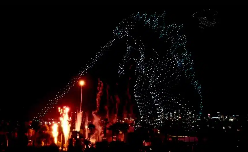 Night drone show creating a giant monster outline above the city skyline.