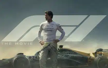 Formula 1 driver standing beside a race car in movie poster.