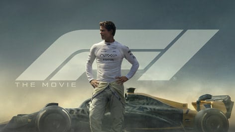 Formula 1 driver standing beside a race car in movie poster.