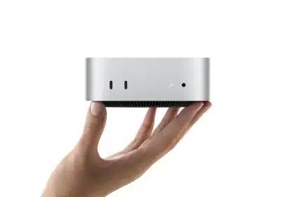 Hand holding a compact silver Mac mini computer.
